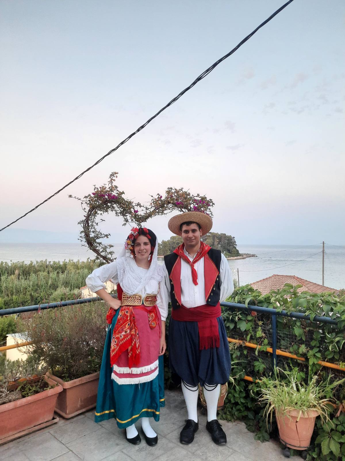 A woman in Corfiot costume on the shore at sunset.